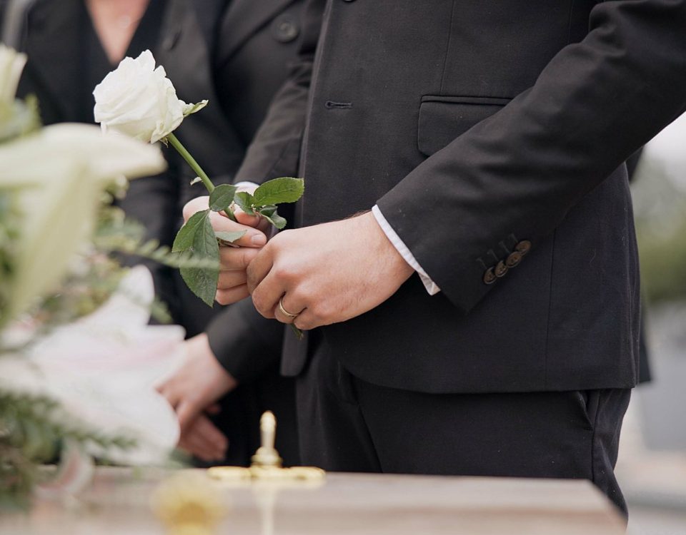 Uczestnik ceremonii pogrzebowej trzymający białą różę